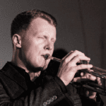 man plays the trumpet soulfully with eyes closed