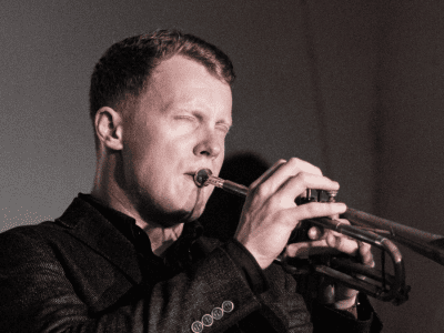 man plays the trumpet soulfully with eyes closed