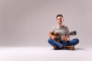 Tyler Cooney sitting down playing guitar