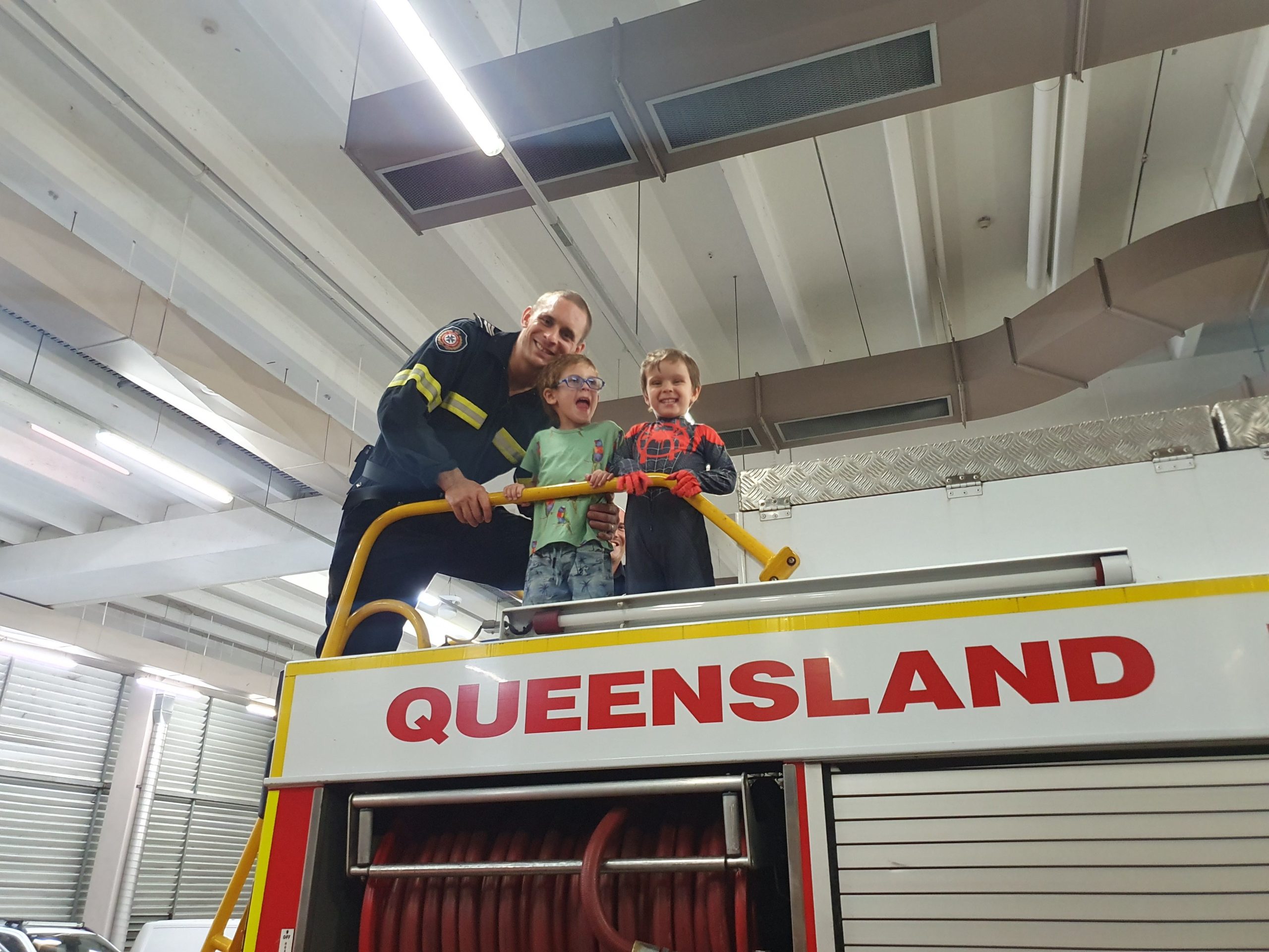 blair on top of a firetruck with his two boys